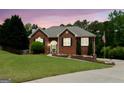 Charming red brick home with manicured lawn, mature trees, under a beautiful twilight sky at 1112 Haver Ct, Mcdonough, GA 30252