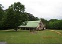 Spacious barn with covered area, surrounded by a large, green field and mature trees at 2997 Happy Hollow Se Dr, Conyers, GA 30094