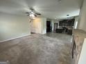 Open-concept living space with carpeted floors, a stone fireplace, and a view into the adjacent kitchen at 960 Spanish Moss Trl, Loganville, GA 30052