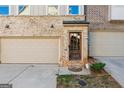 Brick townhome with garage and entry with a wooden front door at 1106 Bakary Ct, Decatur, GA 30032