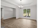 Bright living room featuring new wood floors, large windows, tray ceiling, and stylish chandelier at 3229 Broadnax Mill Rd # 4, Loganville, GA 30052