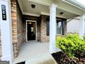 Inviting front porch with brick columns, a well-lit entryway, and a manicured garden bed at 542 Hinton Farm Way, Dacula, GA 30019