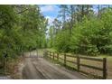 Gated driveway leading through a lush green forest, creating a private and scenic entrance to the property at 5493 Alexanders Lake Sw Rd, Stockbridge, GA 30281