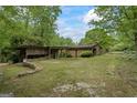 Charming single-story home with a stone facade, wood accents, and a covered carport surrounded by lush greenery at 5493 Alexanders Lake Sw Rd, Stockbridge, GA 30281
