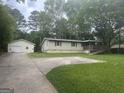 A single-story home showcases an attached garage and ramp access surrounded by a well-maintained lawn and mature trees at 8833 Thomas Rd, Jonesboro, GA 30238