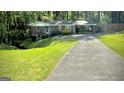 A well-maintained home with a carport and long driveway, surrounded by a green lawn and trees at 1655 Tryon Ne Rd, Brookhaven, GA 30319