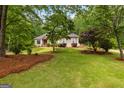 Beautiful front exterior with lush green lawn, mature trees, and charming landscaping, complementing the home's design at 40 High St, Sharpsburg, GA 30277
