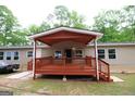 Rear exterior showcasing a covered porch, vinyl siding, and trees in the background at 208 Holliday Way, Carrollton, GA 30116