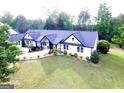 Aerial view of a charming white farmhouse-style home with a lush green lawn and manicured landscaping at 3550 N Bogan Rd, Buford, GA 30519
