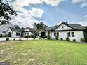 Beautiful two-story farmhouse with a lush green lawn and manicured landscaping on a sunny day at 3550 N Bogan Rd, Buford, GA 30519
