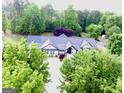 Aerial view of a charming two-story home with lush landscaping and a circular driveway surrounded by trees at 3550 N Bogan Rd, Buford, GA 30519