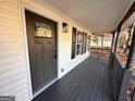 Inviting covered front porch with gray wood floors and charming black door at 473 Amy Blvd, Temple, GA 30179