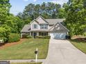 Inviting home exterior with lush green lawn, mature trees, and a well-maintained driveway at 3129 Oak Ridge Ln, Loganville, GA 30052