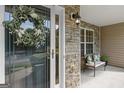 Cozy front porch with stone accent wall, seating, and decorative wreath on the glass front door at 3129 Oak Ridge Ln, Loganville, GA 30052