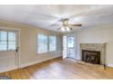 Living room with hardwood floors, a stone fireplace, ceiling fan, and natural light from the windows at 1236 Stone Mountain Lithonia Rd, Lithonia, GA 30058