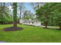 Lovely white home with shutters has an attached garage, a large grassy yard, and beautiful mature trees at 4327 Welligton Hill Ln, Snellville, GA 30039