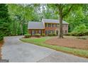 Classic brick home with mature landscaping, a winding driveway, and a serene wooded backdrop at 120 Hermitage Pl, Peachtree City, GA 30269