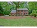 Attractive two-story brick house with black shutters surrounded by lush greenery and a well-maintained lawn at 120 Hermitage Pl, Peachtree City, GA 30269