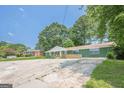 Charming ranch-style home with a painted brick facade, a front porch with wooden railings, and a spacious concrete parking area at 4806 Rockbridge Rd, Stone Mountain, GA 30083