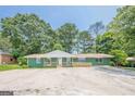 Charming ranch-style home with a painted brick facade, a front porch with wooden railings, and a spacious concrete parking area at 4806 Rockbridge Rd, Stone Mountain, GA 30083