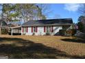 Front exterior of a single story house with a dark roof, shutters, a carport and a manicured lawn at 3875 Grand Prix St, Cumming, GA 30041