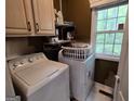 Functional laundry room with cabinetry, shelving, washer, and dryer near a bright window at 80 Jacksons Vly, Sharpsburg, GA 30277