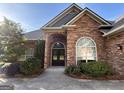 Elegant brick home showcasing an arched entrance with glass-paned doors and a well-manicured landscape at 6504 Cedar Mountain Rd, Douglasville, GA 30134