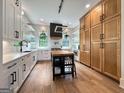 Bright kitchen with white cabinetry, light wood floors, and a center island with butcher block countertop at 300 Mado Ln # 329, Chattahoochee Hills, GA 30268