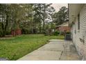 View of a spacious backyard with a concrete patio and a storage shed near the treeline at 7017 Sun Valley Way, Riverdale, GA 30274