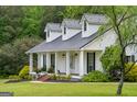 This stunning home has a metal roof, front porch, and lovely landscaping at 333 Old Carrollton Rd, Roopville, GA 30170
