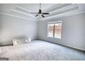 Spacious bedroom with tray ceiling, carpet floor, and large window for natural light at 695 Park Place Way, Social Circle, GA 30025