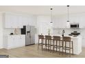 Modern kitchen features white cabinets, stainless steel appliances, a center island, and bar stool seating at 782 Grande Bishop Dr, Fairburn, GA 30213
