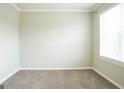 Empty bedroom with neutral carpet, freshly painted walls, and a bright window at 65 Heaton Place Trl, Covington, GA 30016