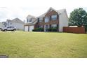 Exterior view of a brick two-story home with a well-maintained lawn and a fenced perimeter at 65 Heaton Place Trl, Covington, GA 30016