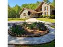 Landscaped front yard with a circular flower bed filled with vibrant purple flowers at 1685 Bailey Creek Sw Rd, Conyers, GA 30094