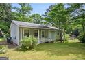 Cozy home with light siding, white trim, a covered porch, and a lush green lawn in a tranquil, wooded setting at 3580 Dorris Cir, Douglasville, GA 30135