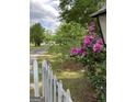 Picturesque yard featuring a white picket fence and vibrant pink flowers along a paved driveway at 854 Clearwater Rd, Sharpsburg, GA 30277