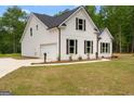 The charming white home has an attached garage, complementing the lush green lawn at 115 Oak Road, Locust Grove, GA 30248