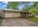 A brick single story home featuring a metal roof, mature shade trees and an attached two car garage at 235 Castlegate Cir, Carrollton, GA 30116