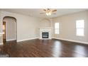 Cozy living room with a fireplace, ceiling fan, hardwood floors, and two bright windows at 7481 Absinth Dr, Atlanta, GA 30349