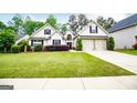 Charming home featuring a two-car garage, complemented by lush green landscaping and manicured bushes at 1015 Buckeye Ln, Villa Rica, GA 30180