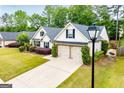 Overhead shot of charming home featuring a two-car garage, complemented by lush green landscaping and manicured bushes at 1015 Buckeye Ln, Villa Rica, GA 30180