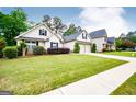 Charming home featuring a two-car garage, complemented by lush green landscaping and manicured bushes at 1015 Buckeye Ln, Villa Rica, GA 30180