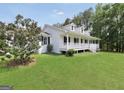 Lovely white home featuring dormer windows, covered porch, and a green lawn at 138 Sam Solomon Rd, Locust Grove, GA 30248