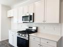 Bright white kitchen features stainless steel appliances, a stylish backsplash, and quartz countertops at 3865 Shelleydale Dr # 82, Powder Springs, GA 30127