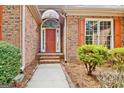 Close up of the charming brick home featuring a front door with decorative shutters and surrounding landscaping at 250 Kari Glen Dr, Fayetteville, GA 30215