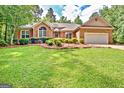 Charming single-story brick home featuring an attached garage, a well-manicured lawn and mature trees at 250 Kari Glen Dr, Fayetteville, GA 30215
