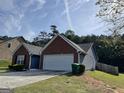 View of the side of the home showcasing a two-car garage and wooded surroundings at 4092 River Mist Ct, Lithonia, GA 30038