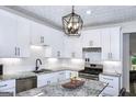 Bright kitchen features stainless steel appliances, granite countertops, white cabinets and modern pendant lighting at 2566 Summit Cove Dr, Duluth, GA 30097