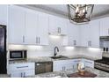 Bright kitchen features stainless steel appliances, granite countertops, white cabinets and modern pendant lighting at 2566 Summit Cove Dr, Duluth, GA 30097